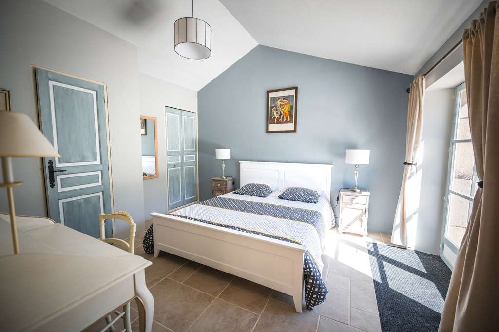 Bright view of the Aurore room at the L’Heure Exquise lodge, decorated with pastel tones, white wooden furniture, and a large double bed