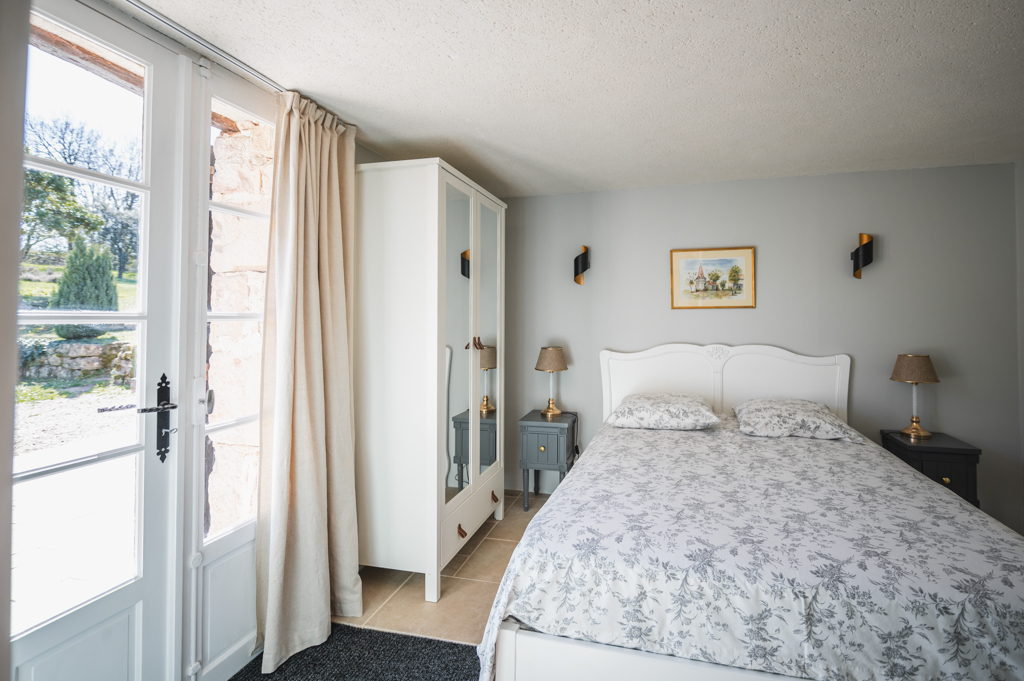 Crépuscule room at the L’Heure Exquise lodge, with a double bed, a large white wardrobe and a view of the garden.