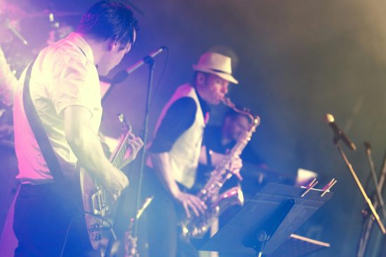 Photo de musiciens en plein concert, jouant sur scène dans une ambiance vibrante et festive.