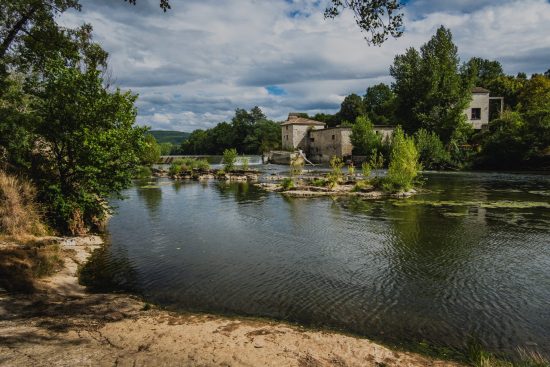 Photo of the Moulin des Bordes on the banks of the Aveyron river, surrounded by greenery and a peaceful natural landscape