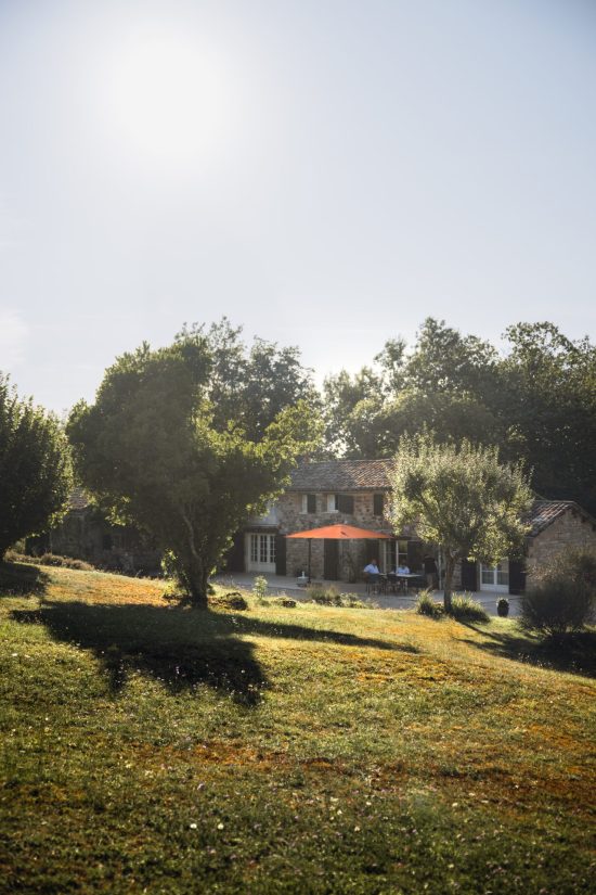 Vertical photo of the L’Heure Exquise lodge, highlighting its stone facade and sunny terrace.