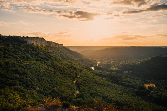 Photo of the Roc d'Anglars with a sunset, the Aveyron river and the village of Saint-Antonin-Noble-Val in the background.