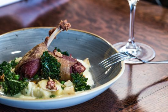 Photo of a gourmet plate with golden duck confit and creamy puree, served with a tasty sauce