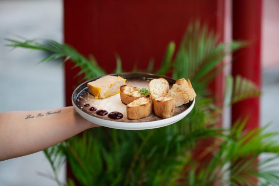 Photo of an elegant plate with a slice of foie gras accompanied by toasted bread and a sweet condiment