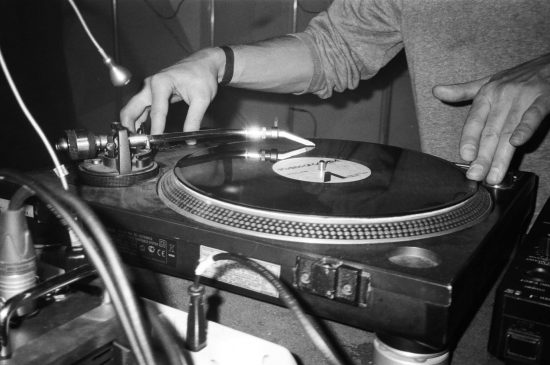 Photo d’un DJ mixant sur des platines vinyles, ajustant les disques avec précision pour créer une ambiance unique