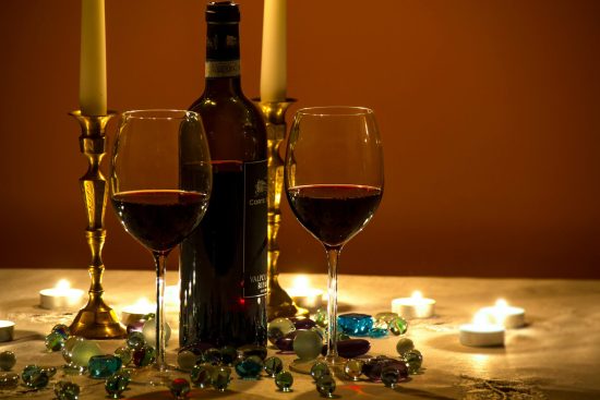 Photo of two stemmed glasses filled with wine with a bottle placed next to them, creating a warm and elegant ambiance
